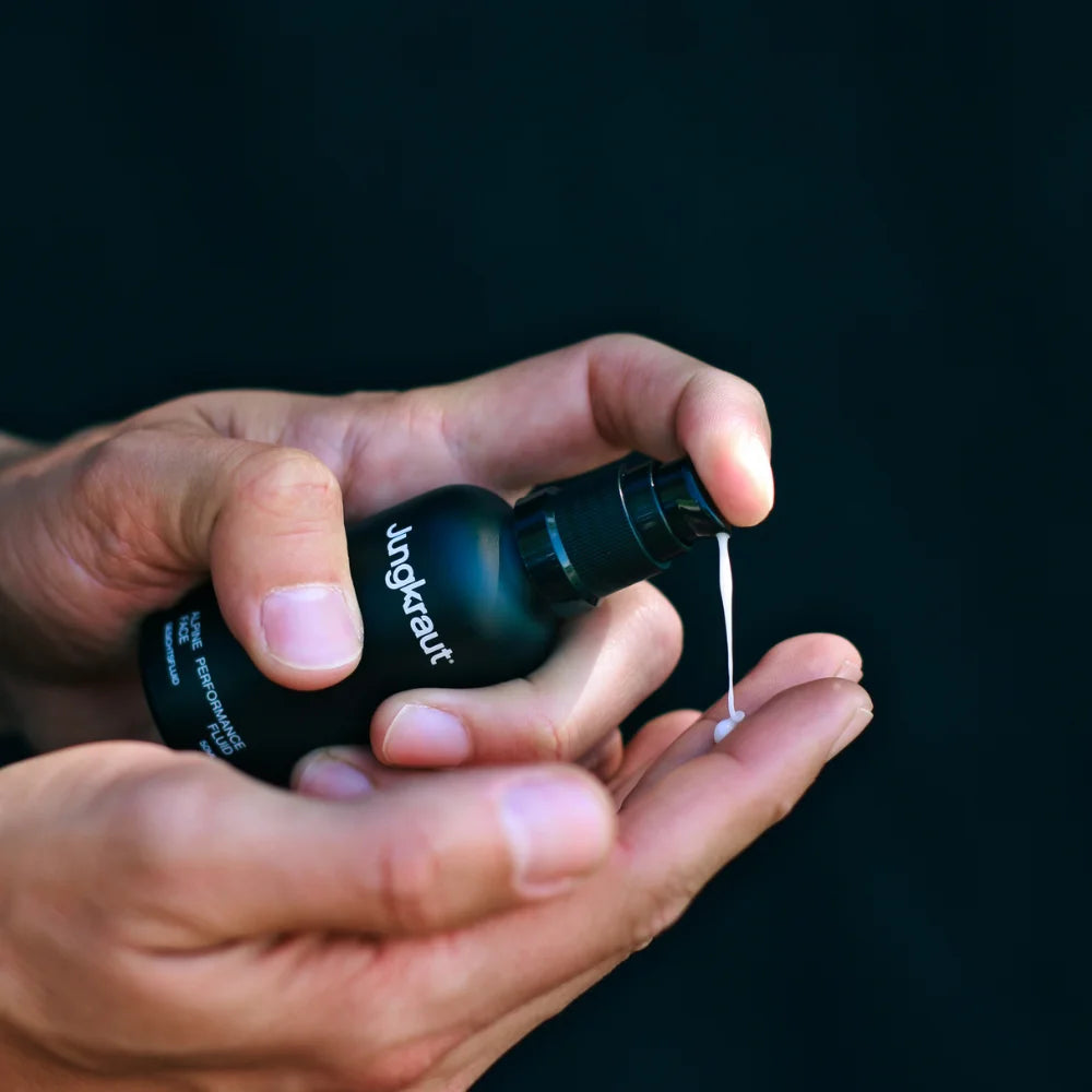 Hände dosieren Jungkraut Alpine Performance Gesichtsfluid für Männer, cremige Textur aus schwarzem Pumpspender